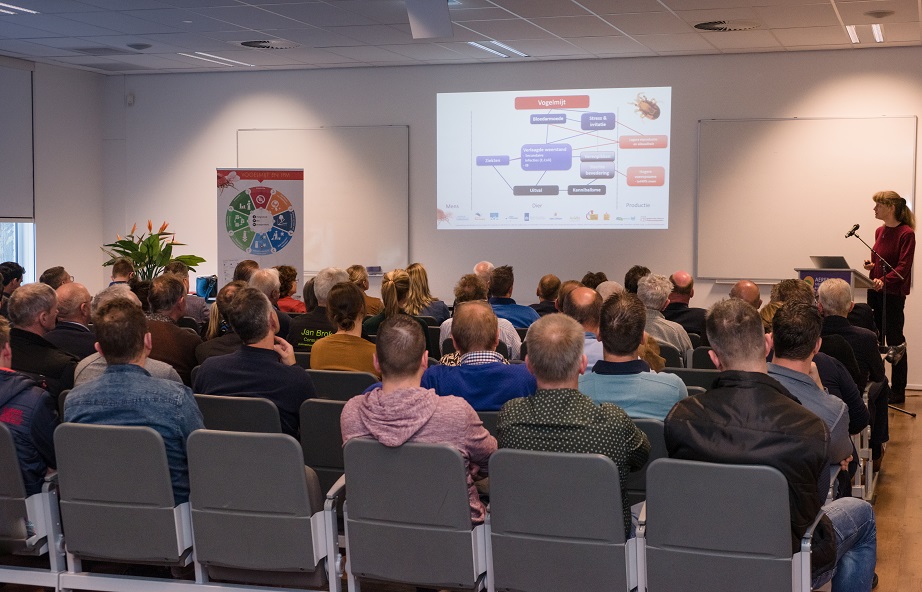 Thea van Niekerk geeft presentatie over vogelmijt in een zaal vol mensen